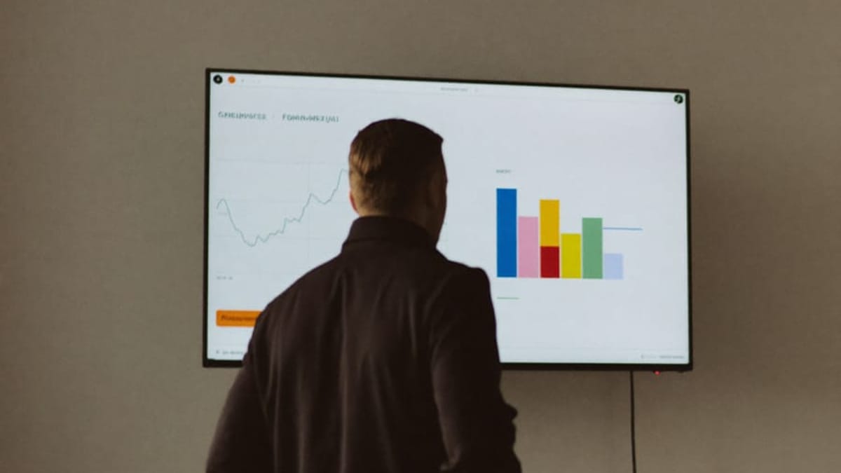Un panel de datos iluminado en ámbar al que mira un empresario de espaldas