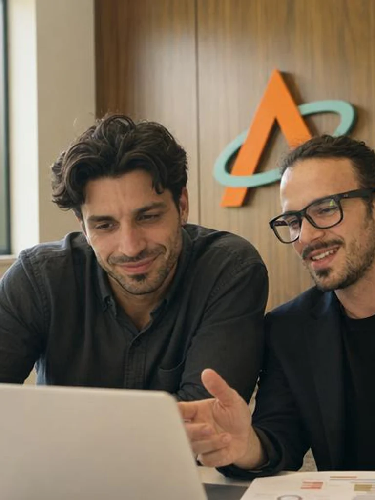 Víctor Torres y David Montesinos trabajando juntos frente al portátil en la oficina.
